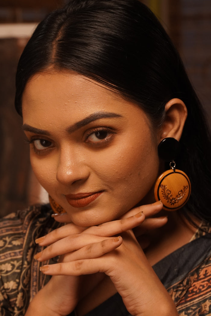 Kalika wooden earrings worn with a printed indigo saree — engraved Boxwood round below an Ebony disc