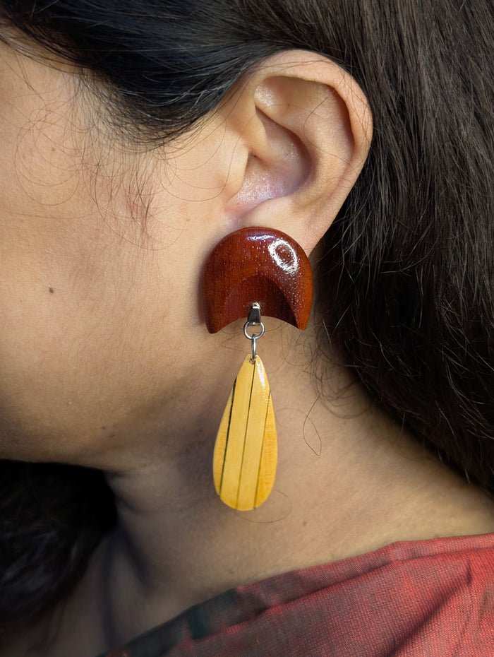 Oorja wooden earrings worn — Padauk crescent above a Maple teardrop inlaid with Ebony lines